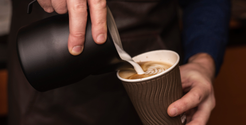 close-up-person-pouring-milk-into-coffee-cup